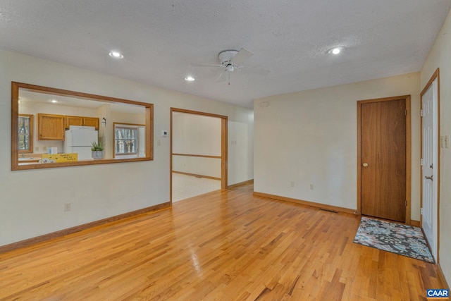 empty room with ceiling fan, a textured ceiling, and light hardwood / wood-style floors