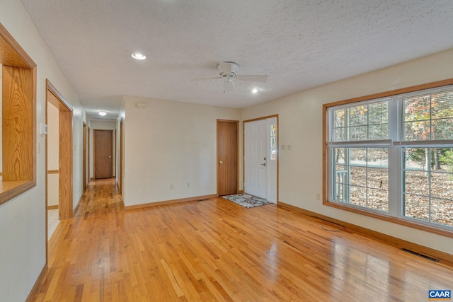 empty room with light wood-type flooring, a textured ceiling, and ceiling fan