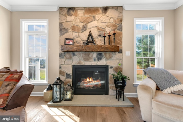 living room with ornamental molding, a fireplace, plenty of natural light, and wood-type flooring