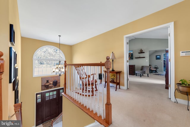 hallway with a chandelier, vaulted ceiling, and carpet flooring