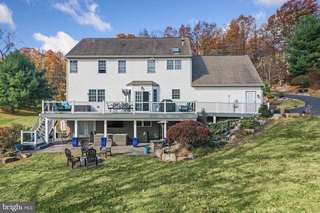 rear view of house featuring a deck, an outdoor living space with a fire pit, a patio, and a lawn