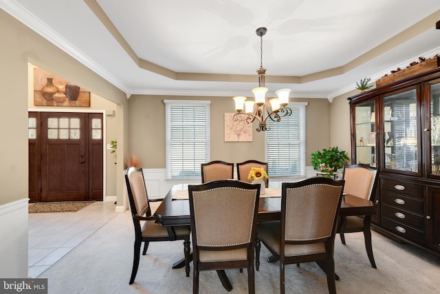 dining room featuring ornamental molding, light tile patterned floors, an inviting chandelier, and a tray ceiling