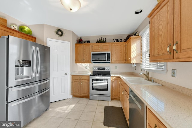 kitchen with light stone countertops, appliances with stainless steel finishes, sink, and light tile patterned floors