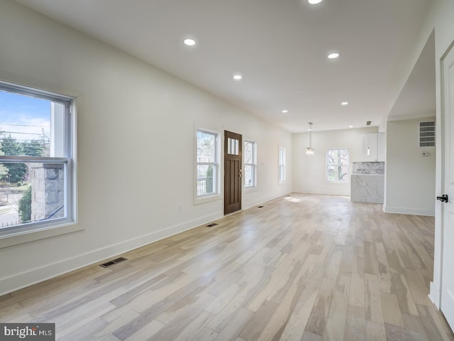 unfurnished living room featuring a wealth of natural light and light hardwood / wood-style floors