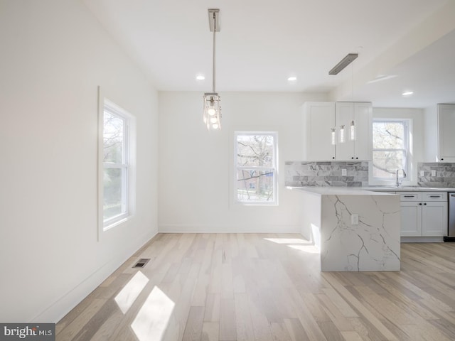 kitchen with pendant lighting, decorative backsplash, light hardwood / wood-style floors, and white cabinets