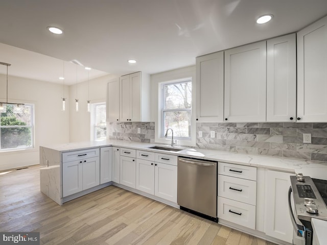 kitchen with light hardwood / wood-style floors, white cabinets, sink, appliances with stainless steel finishes, and decorative light fixtures