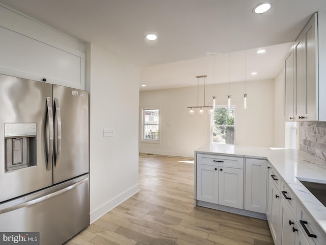 kitchen with white cabinets, stainless steel refrigerator with ice dispenser, light wood-type flooring, and light stone counters