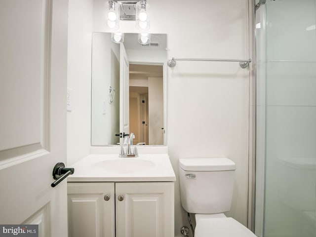 bathroom featuring toilet, vanity, and a shower with door