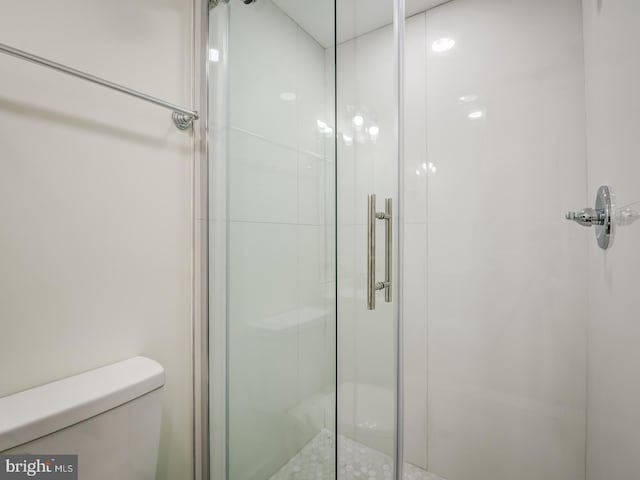 bathroom with a shower with door and toilet