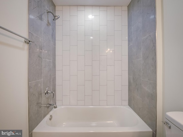 bathroom featuring tiled shower / bath and toilet