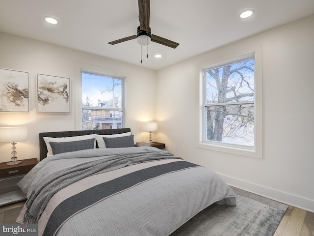 bedroom featuring multiple windows, hardwood / wood-style flooring, and ceiling fan