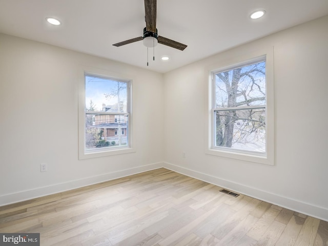 spare room featuring a wealth of natural light, ceiling fan, and light hardwood / wood-style floors