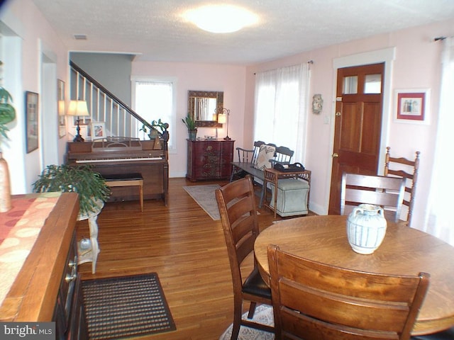 dining room with dark hardwood / wood-style floors, a healthy amount of sunlight, and a textured ceiling