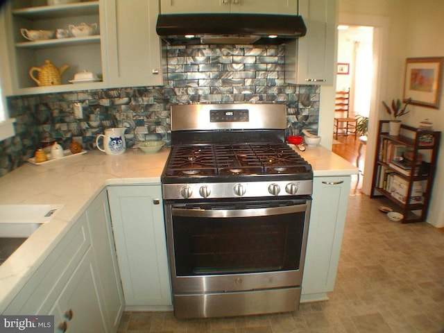 kitchen featuring tasteful backsplash, light stone countertops, gas range, and green cabinetry