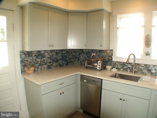 kitchen featuring stainless steel dishwasher, sink, and backsplash