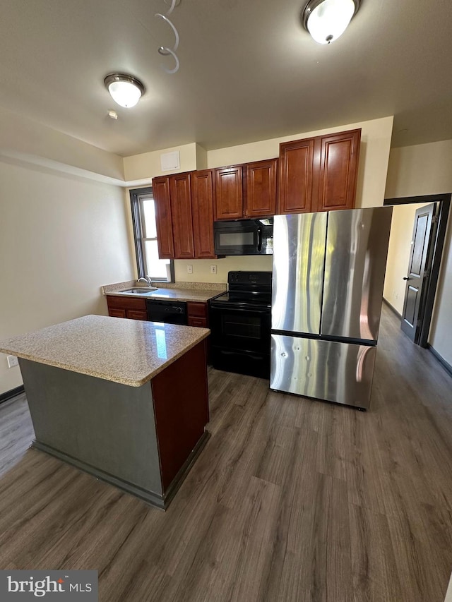 kitchen featuring black appliances, dark hardwood / wood-style floors, a kitchen island, and sink