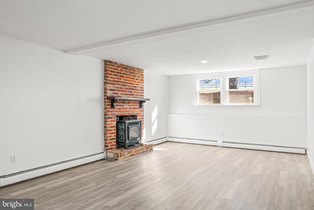 unfurnished living room featuring light wood-type flooring, a wood stove, and a baseboard heating unit