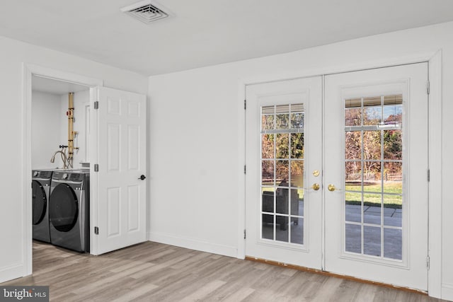 laundry area featuring washing machine and dryer, light hardwood / wood-style flooring, and french doors