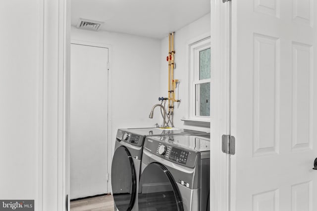 washroom with washing machine and dryer and light hardwood / wood-style floors