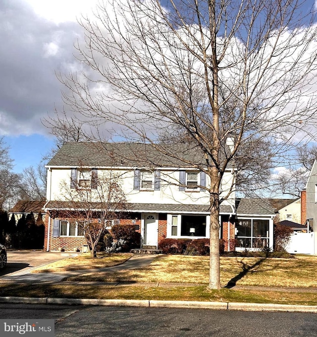 view of front of house with a front yard, a carport, and a sunroom