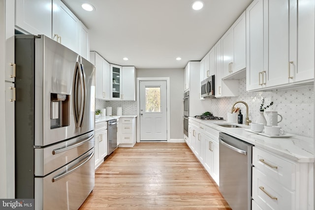 kitchen with sink, white cabinetry, stainless steel appliances, and light hardwood / wood-style flooring