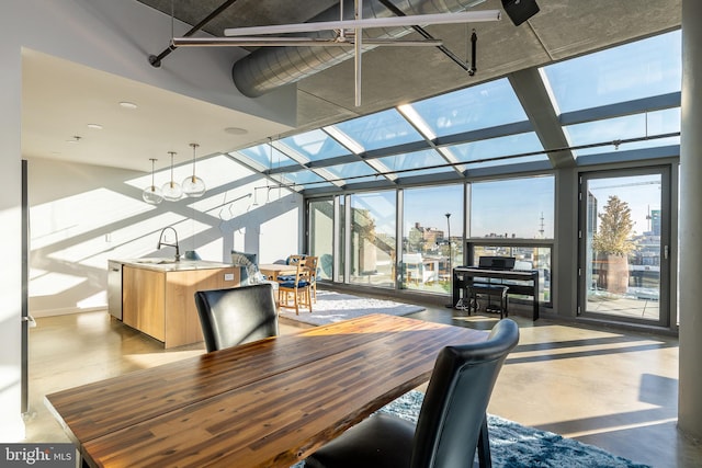 dining space featuring concrete flooring, expansive windows, and sink