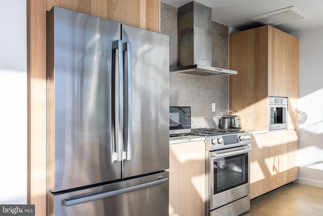 kitchen featuring tasteful backsplash, stainless steel appliances, wall chimney range hood, and light wood-type flooring