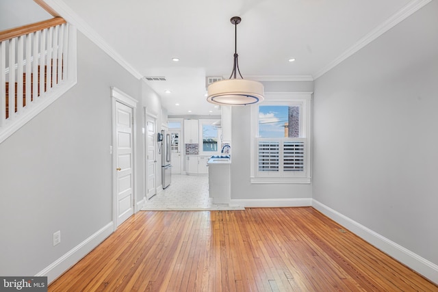 foyer entrance featuring light hardwood / wood-style flooring, ornamental molding, and sink