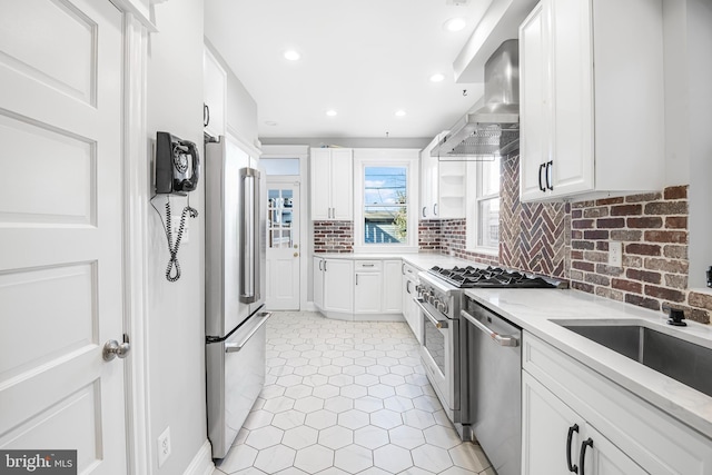 kitchen featuring white cabinetry, sink, wall chimney exhaust hood, decorative backsplash, and appliances with stainless steel finishes