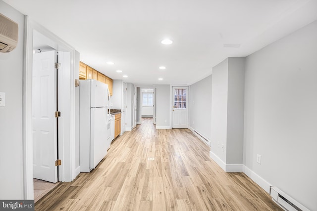 interior space featuring a wall mounted air conditioner, light wood-type flooring, and a baseboard heating unit