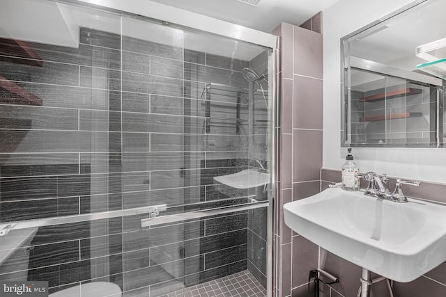 bathroom with tile patterned floors, a shower with shower door, and sink