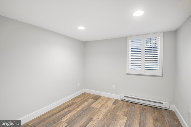 spare room featuring wood-type flooring and a baseboard heating unit