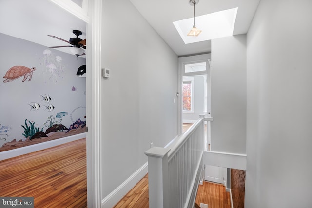 stairs with a skylight, ceiling fan, and hardwood / wood-style floors