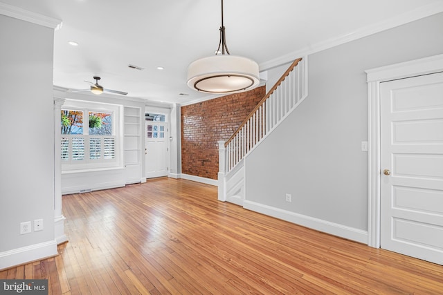 foyer with ceiling fan, ornamental molding, brick wall, and light wood-type flooring