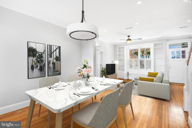 dining space featuring ceiling fan, light hardwood / wood-style flooring, built in features, and ornamental molding