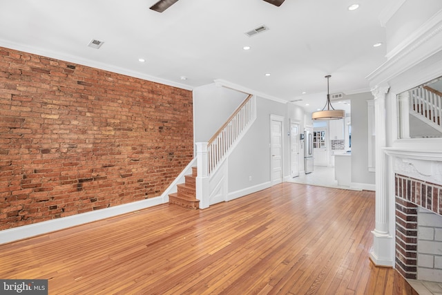 unfurnished living room featuring ornamental molding, brick wall, and light hardwood / wood-style flooring