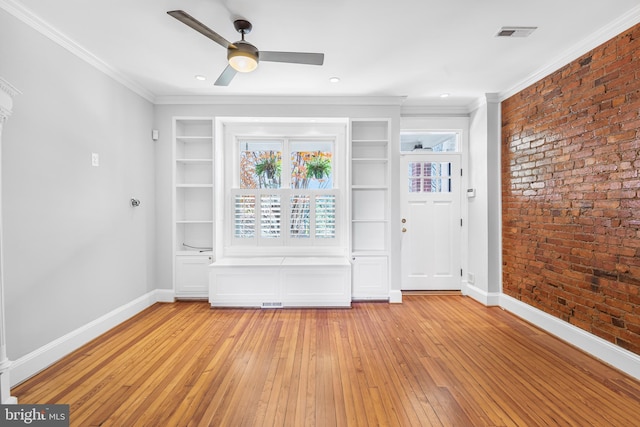 interior space featuring light wood-type flooring, ornamental molding, and brick wall