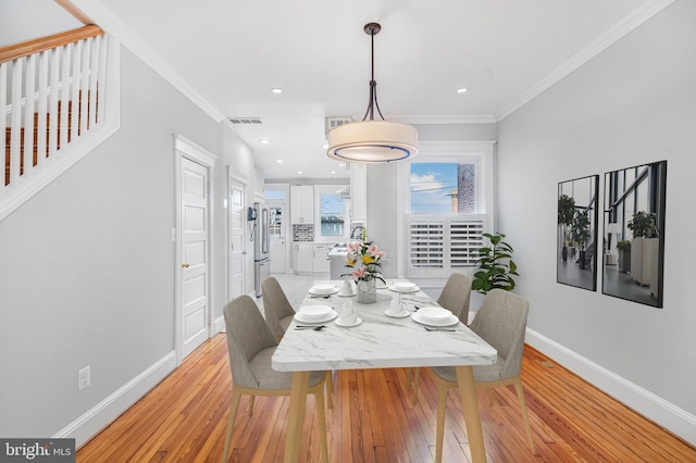 dining space with light hardwood / wood-style flooring and crown molding