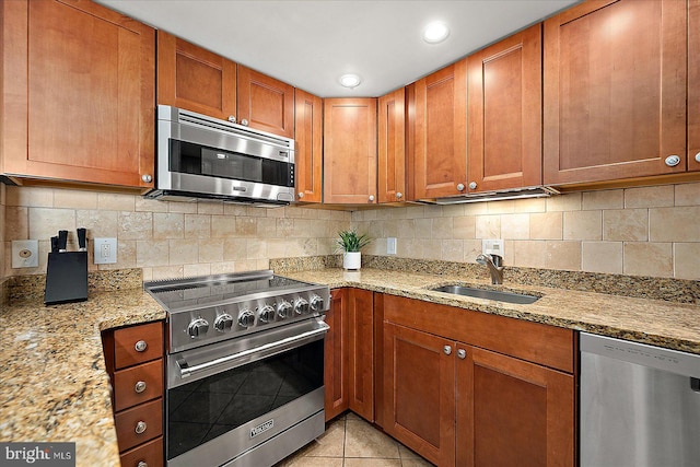 kitchen featuring light tile patterned flooring, sink, light stone counters, appliances with stainless steel finishes, and tasteful backsplash