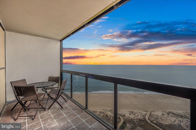 balcony at dusk with a beach view and a water view