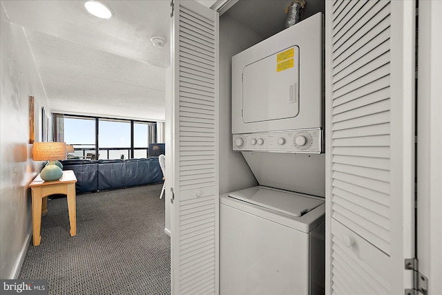 clothes washing area with stacked washer and dryer, a textured ceiling, and carpet