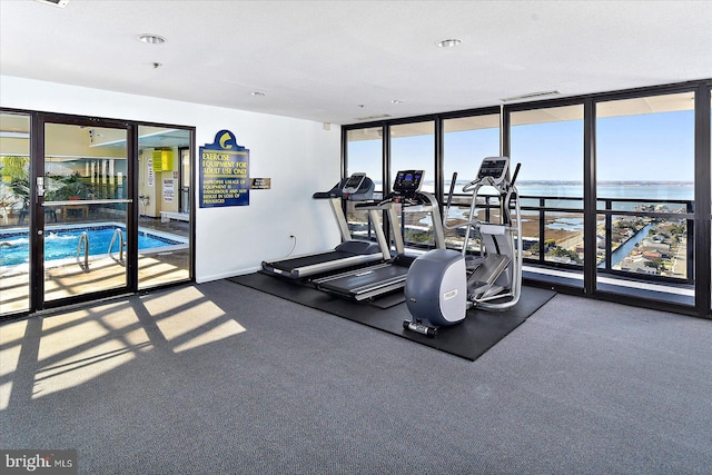 workout area with expansive windows, plenty of natural light, and a water view