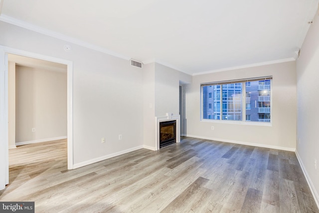 unfurnished living room with ornamental molding and light wood-type flooring