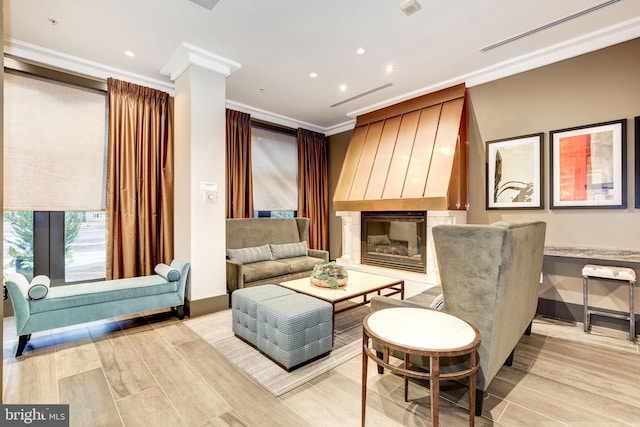 living area featuring a large fireplace, light hardwood / wood-style floors, and ornamental molding