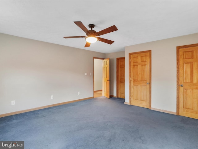 unfurnished bedroom featuring dark colored carpet, two closets, and ceiling fan