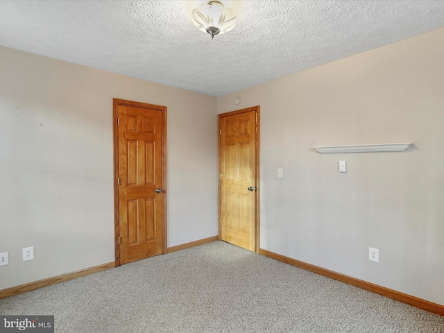 unfurnished room with carpet and a textured ceiling