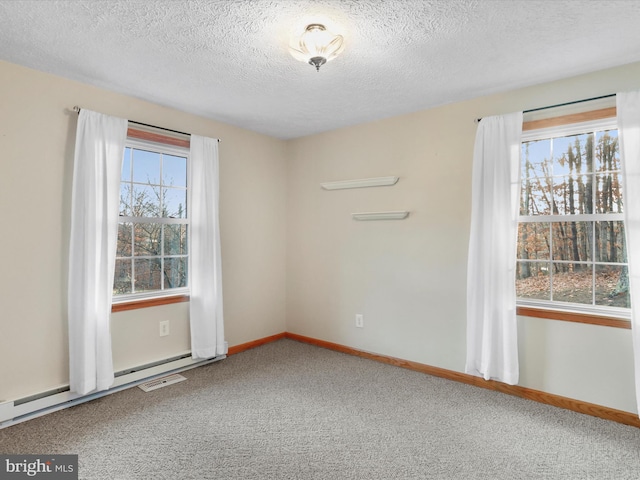 carpeted spare room with a textured ceiling and a baseboard heating unit