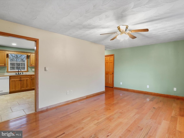 empty room with ceiling fan, sink, and light hardwood / wood-style floors