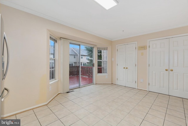 unfurnished bedroom featuring multiple closets, stainless steel fridge, light tile patterned flooring, and ornamental molding