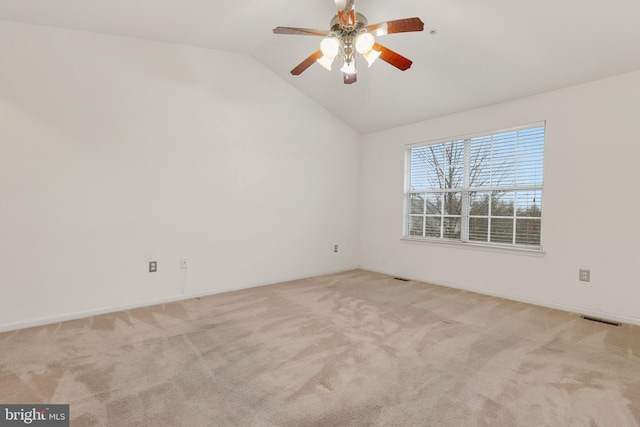 spare room featuring light carpet, vaulted ceiling, and ceiling fan